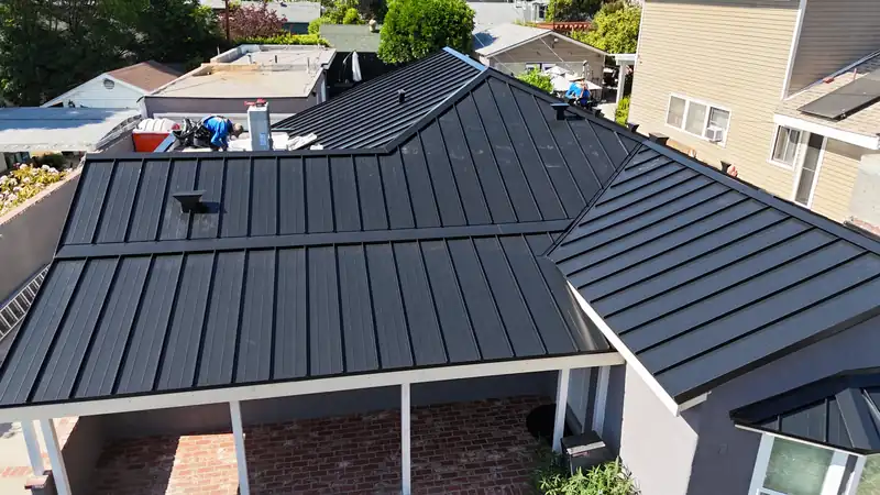 Black standing seam metal roof with hips, valleys and a covered patio, seen from above
